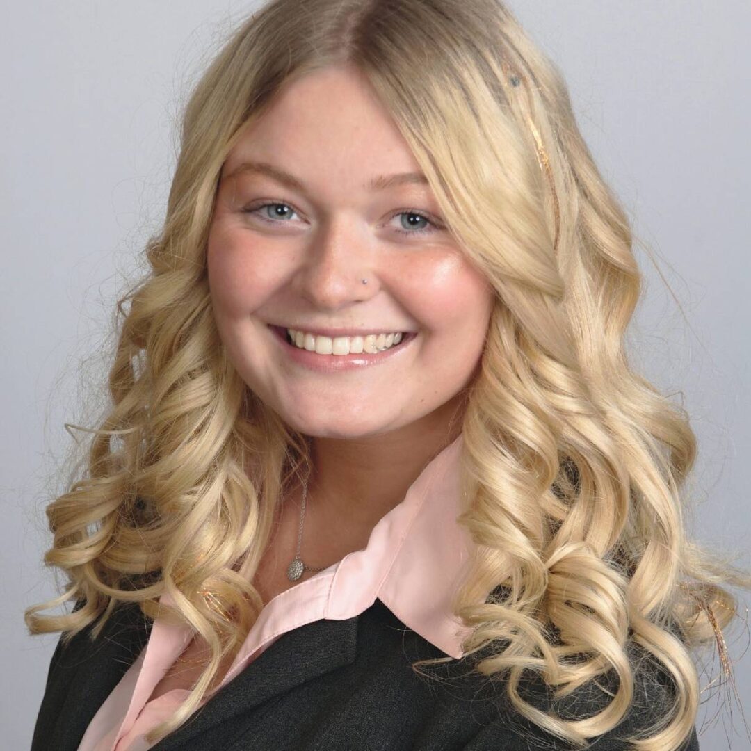 Smiling woman with curly blonde hair in professional attire.